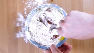 A Person Stirs Flour, Eggs, and Nutella Together in A Blue Mixing Bowl