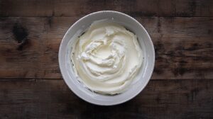 A bowl of smooth, creamy blue cheese dressing set on a rustic wooden surface, ready to be refrigerated