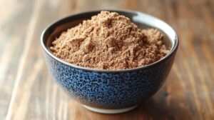 Bowl filled with chocolate protein powder on a wooden table, used as an ingredient in a protein pop tart recipe