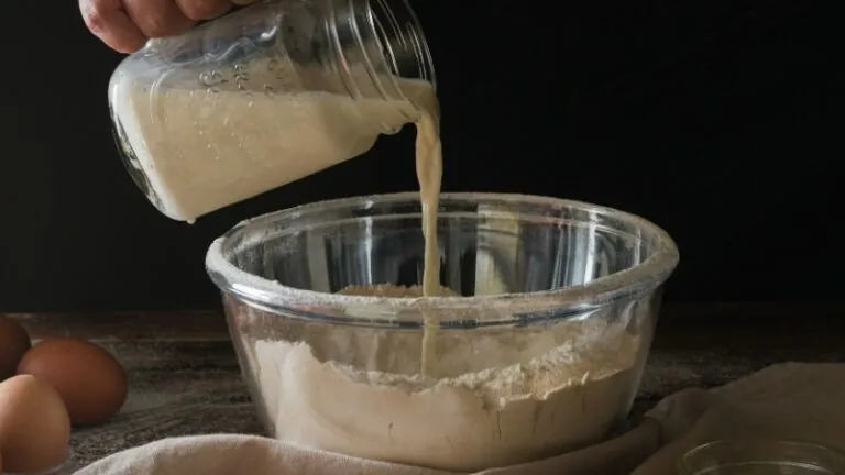 Pouring a buttermilk substitute into a bowl of flour, testing different substitutes for buttermilk in baking