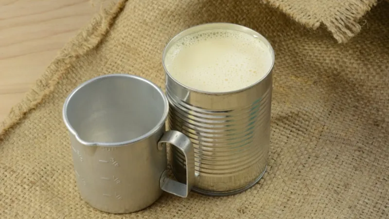 A metal cup and tin filled with plain milk, used as a last-minute substitute for buttermilk in baking