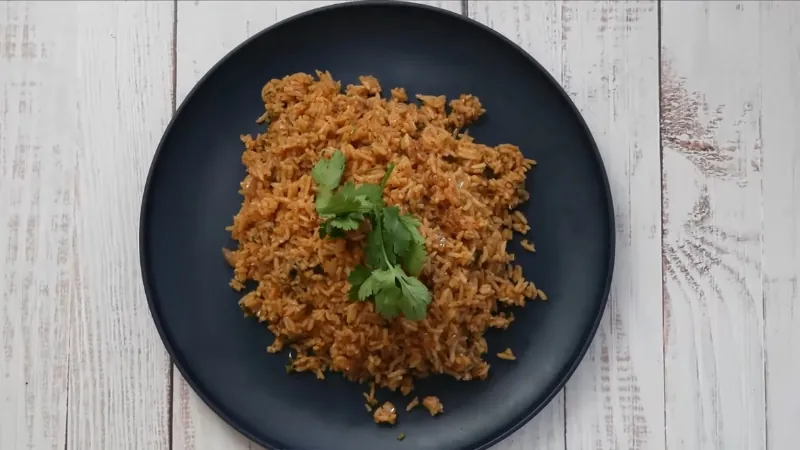 A serving of Moe’s seasoned rice topped with fresh cilantro on a dark plate set on a white wooden table