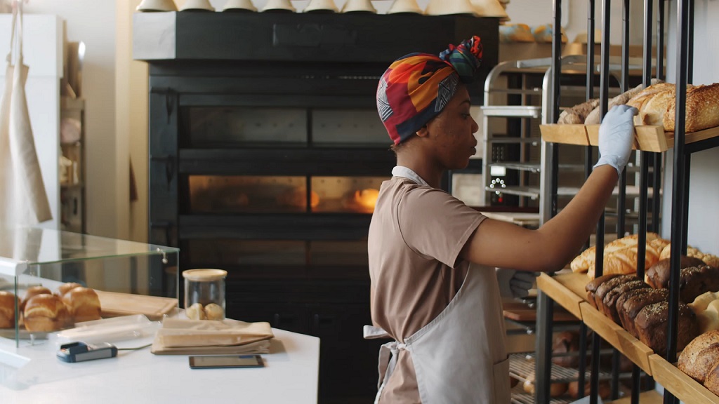 Female baker arranging loaves on shelf