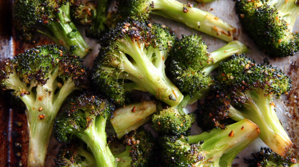 Close-up of roasted broccoli on a baking sheet, seasoned with garlic and spices