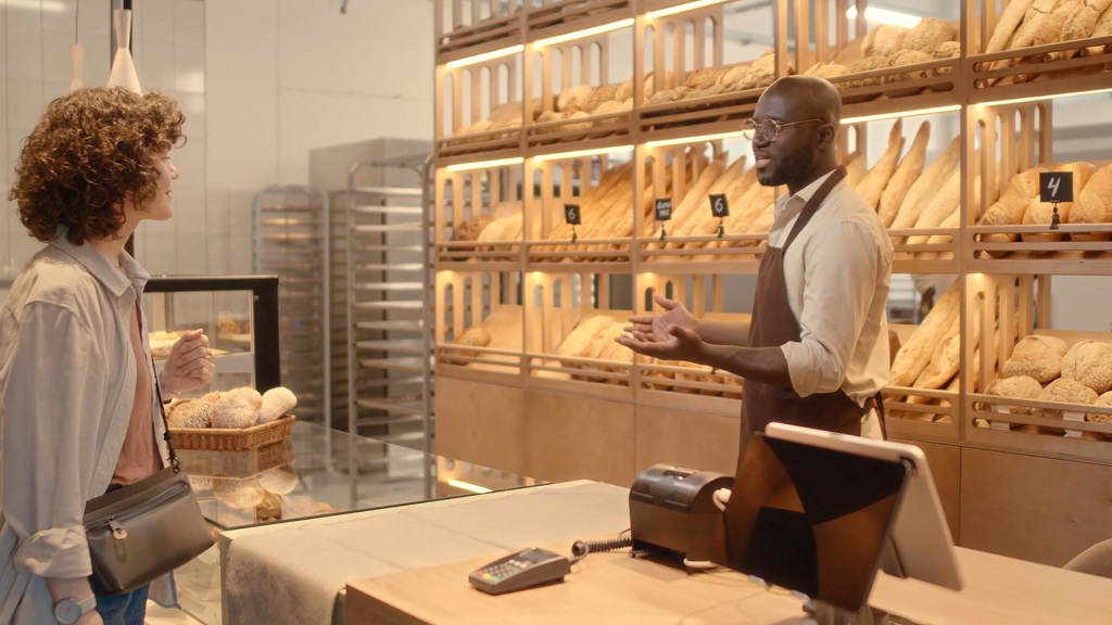 Customer discussing bread options with baker in a shop